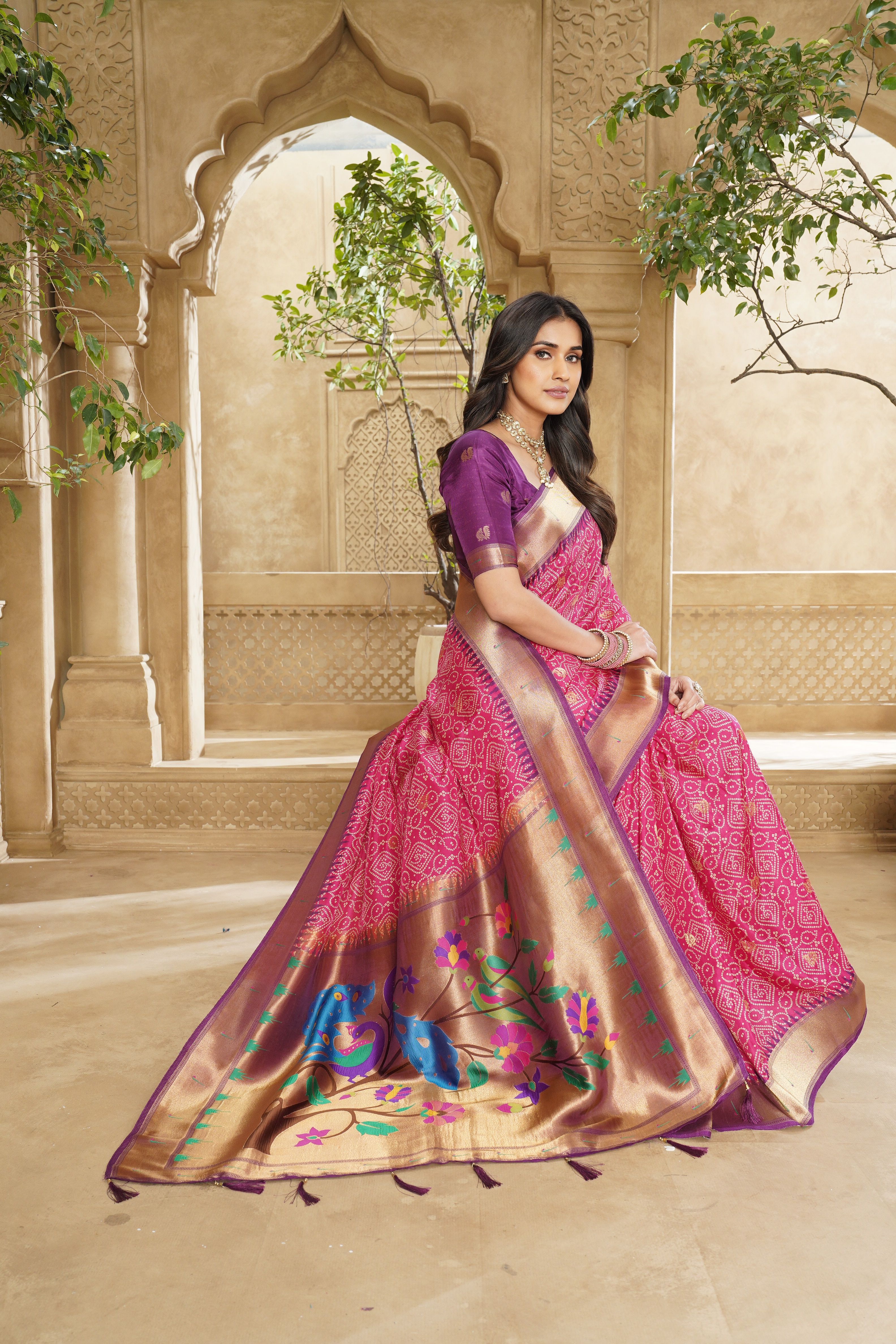 Model wearing a lilac and rose saree beside a carved garden column